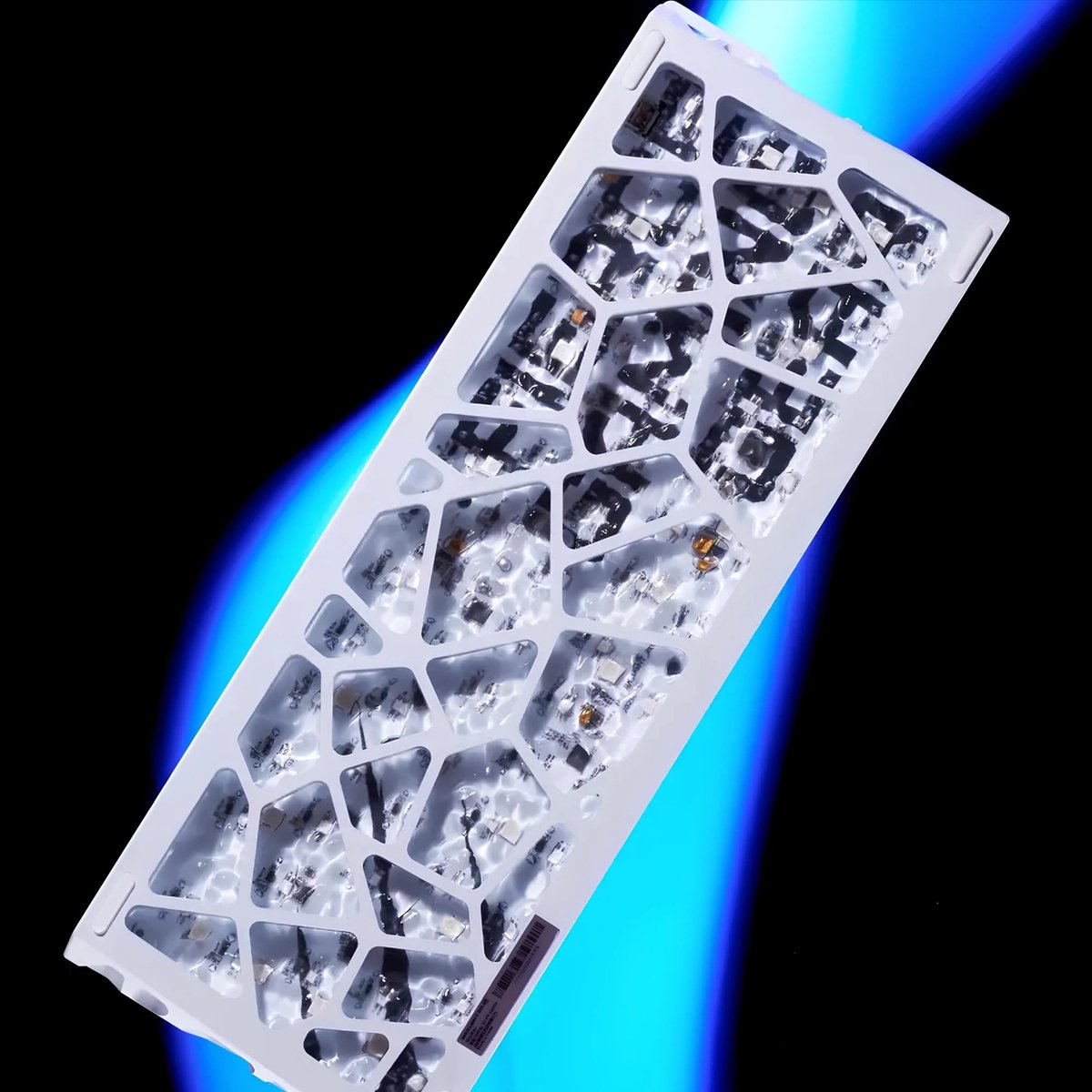 A white keyboard frame with a honeycomb structure, filled with electronic components, against a blue and black gradient background.