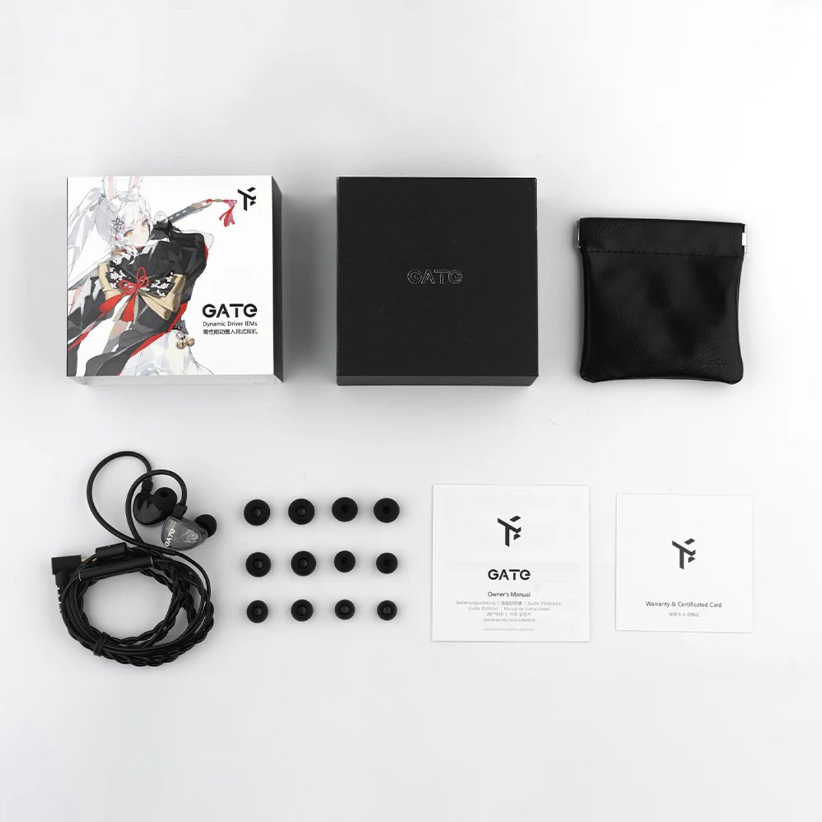 Oortelefoons, dozen en accessoires op een wit oppervlak. De doos heeft een anime-personage. Andere items zijn oordopjes en handleidingen.