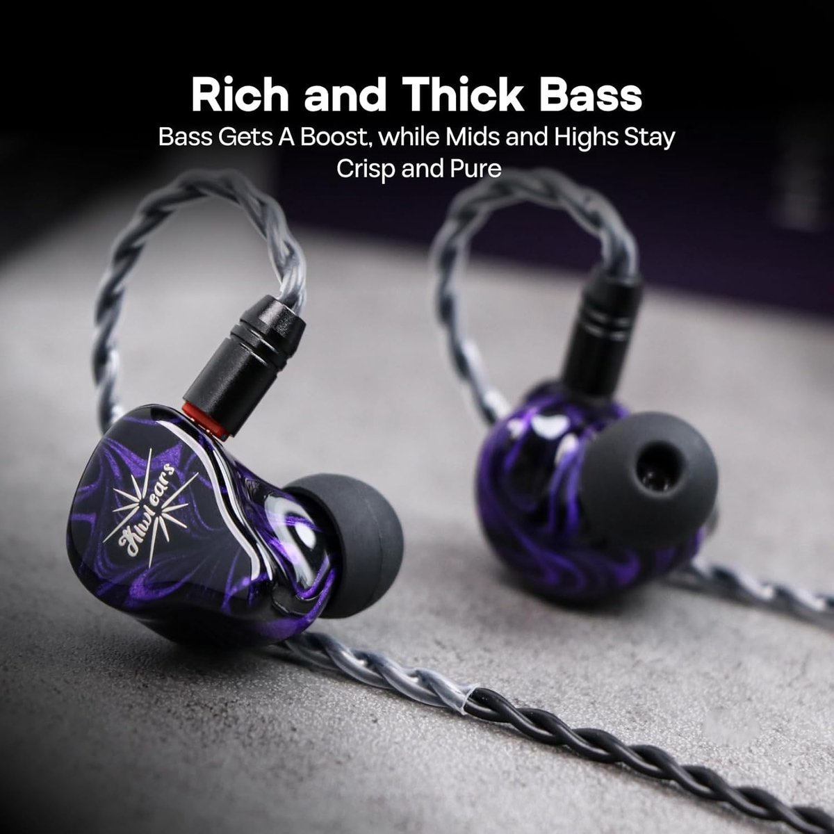 Gros plan de deux écouteurs intra-auriculaires. Ils sont noirs et violets, avec des câbles argentés. Le texte indique 'Rich and Thick Bass'.