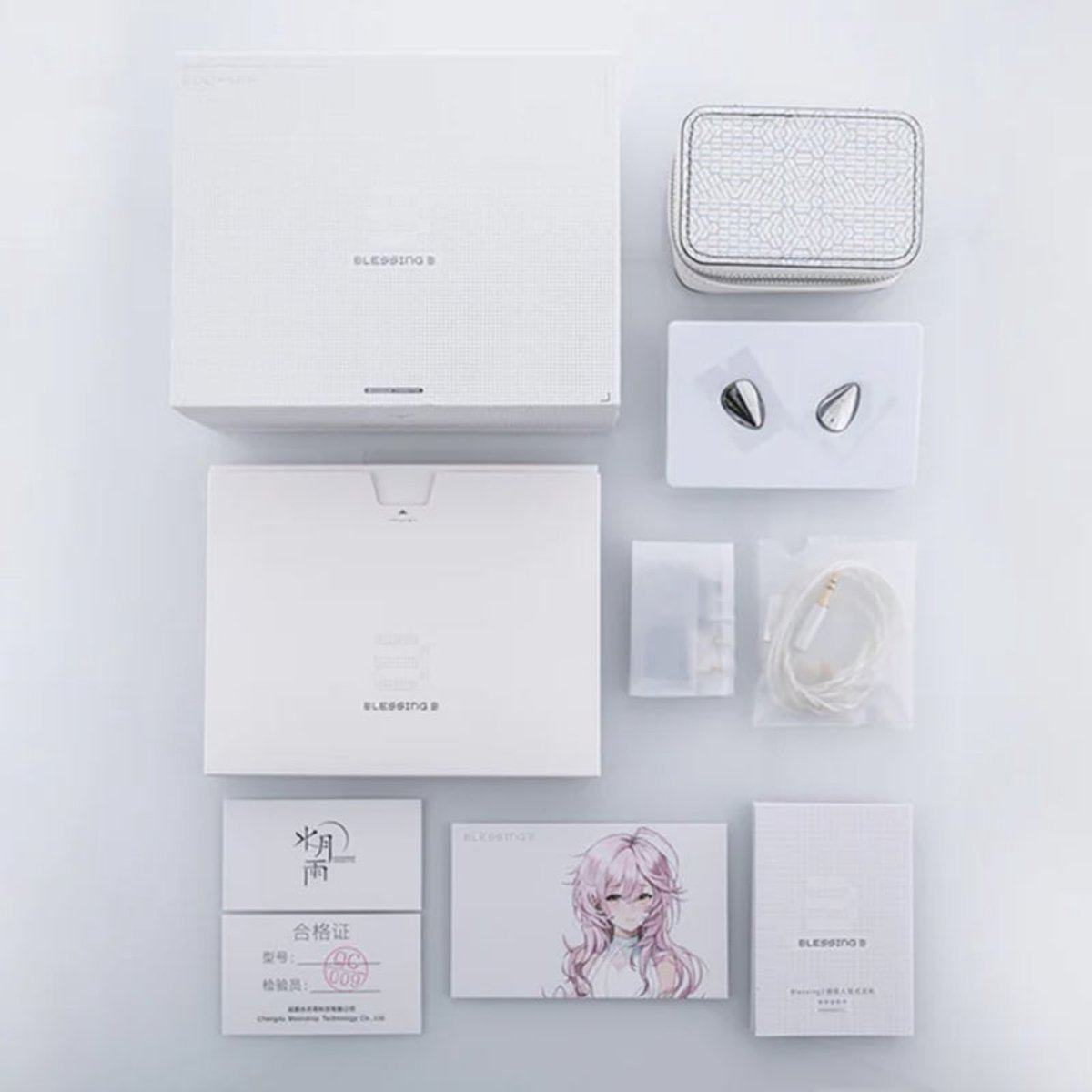 Bovenaanzicht van witte verpakking, etui en accessoires voor oortelefoons. Inclusief oortelefoons, kaarten met tekst en een anime-illustratie op een kaart.