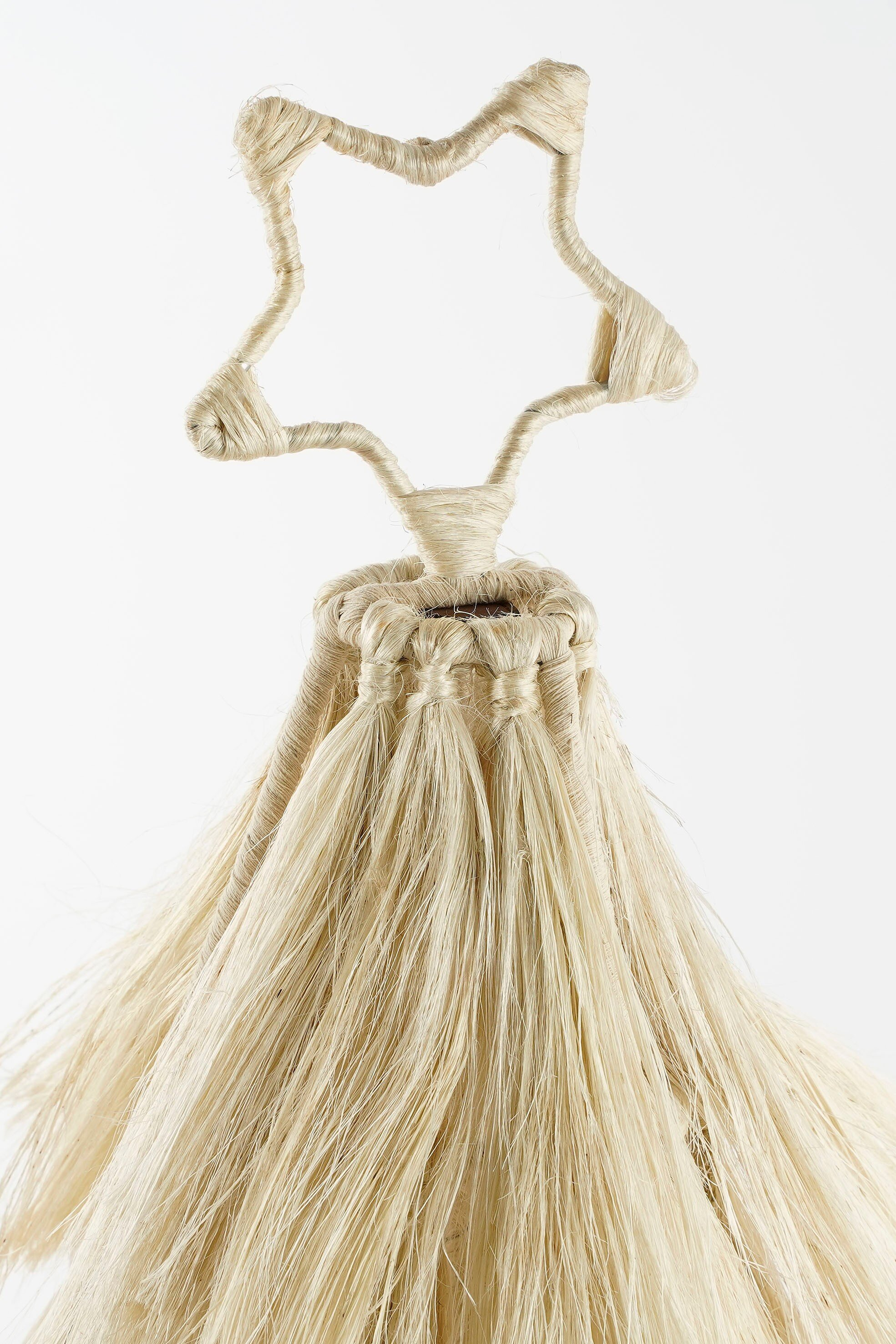 Un ornement en forme d'étoile fait d'un matériau fibreux beige clair. Il a un fond en forme de gland et un fond blanc.