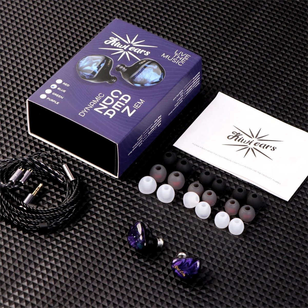 Kulaklık kiti. Kulaklıklar, kulak uçları ve kablo ile desenli bir yüzeyde kutu. Kutuda 'Kiwi ears' ve 'Live the music' yazıyor.