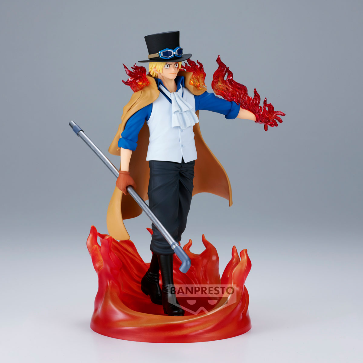 Una figura di un uomo con cappello a cilindro, mantello ed effetti di fuoco. Tiene un bastone. La figura è su una base infuocata.