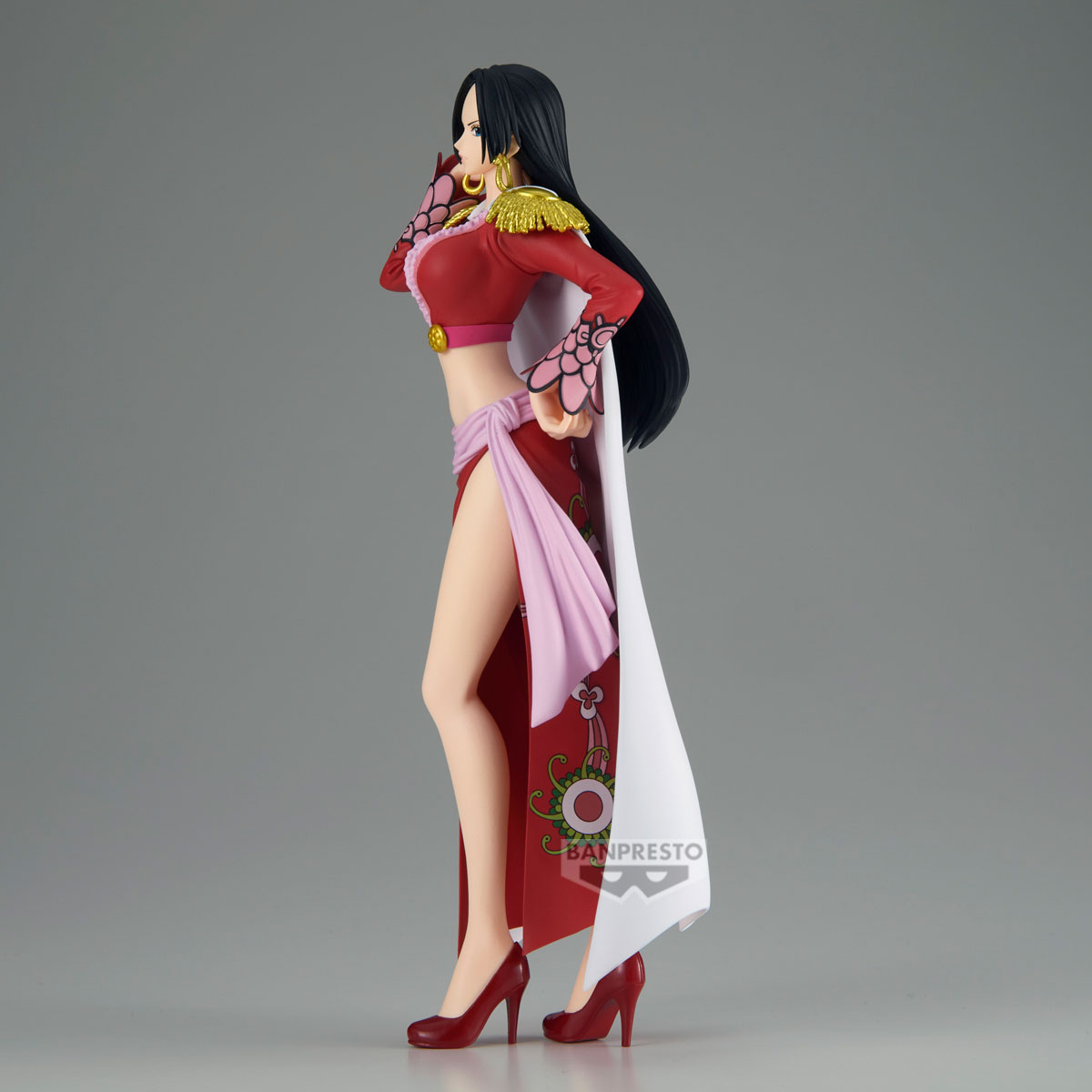 Una figura de una mujer con vestido y tacones rojos. Tiene pelo negro largo y posa con una mano cerca de la cara.