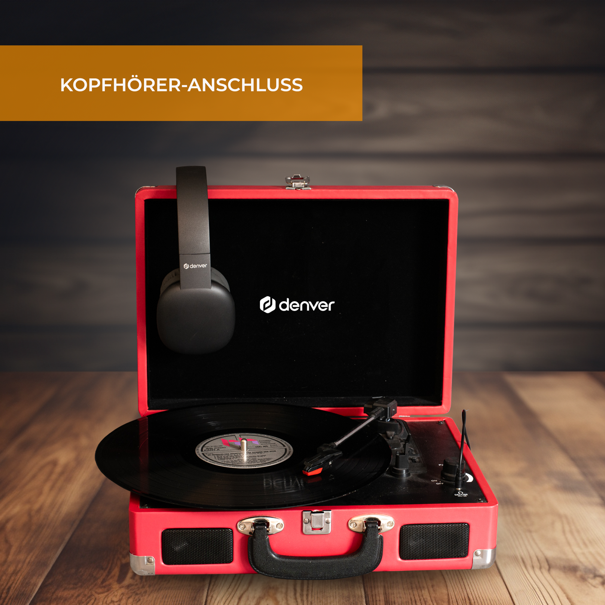 Un tocadiscos rojo con un disco negro. Auriculares negros cuelgan dentro. Fondo de madera.