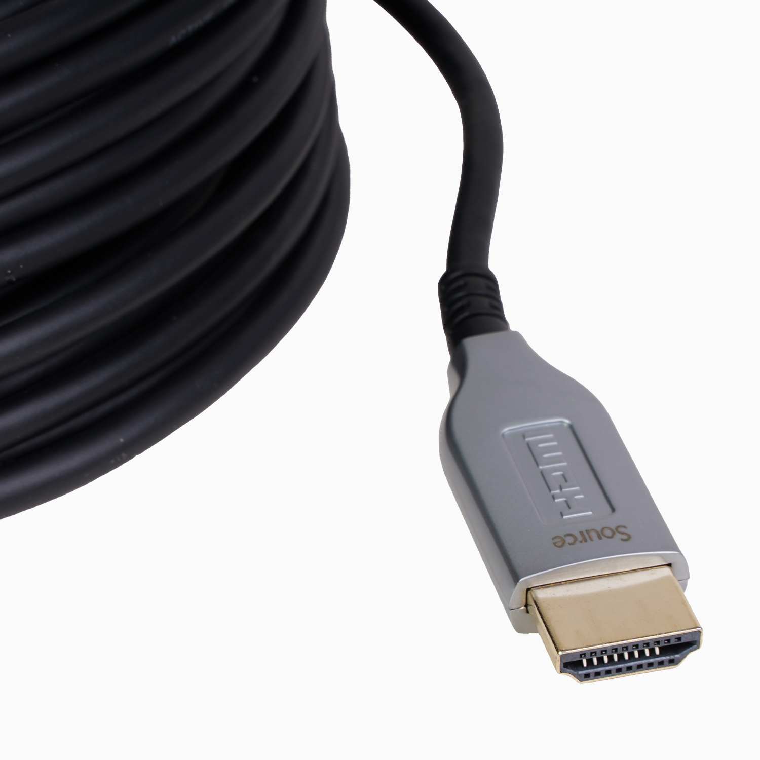 Ein HDMI-Kabel mit einem silbernen Stecker mit der Aufschrift 'Source' und einem goldfarbenen Stecker, mit einem aufgerollten schwarzen Kabel.