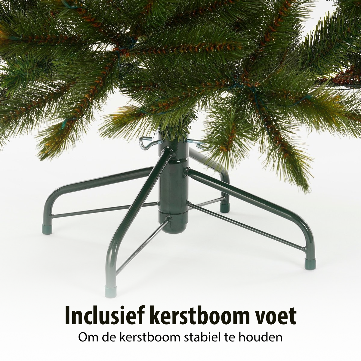A green Christmas tree base with legs, supporting an artificial tree. Text at the bottom says: Includes Christmas tree foot.