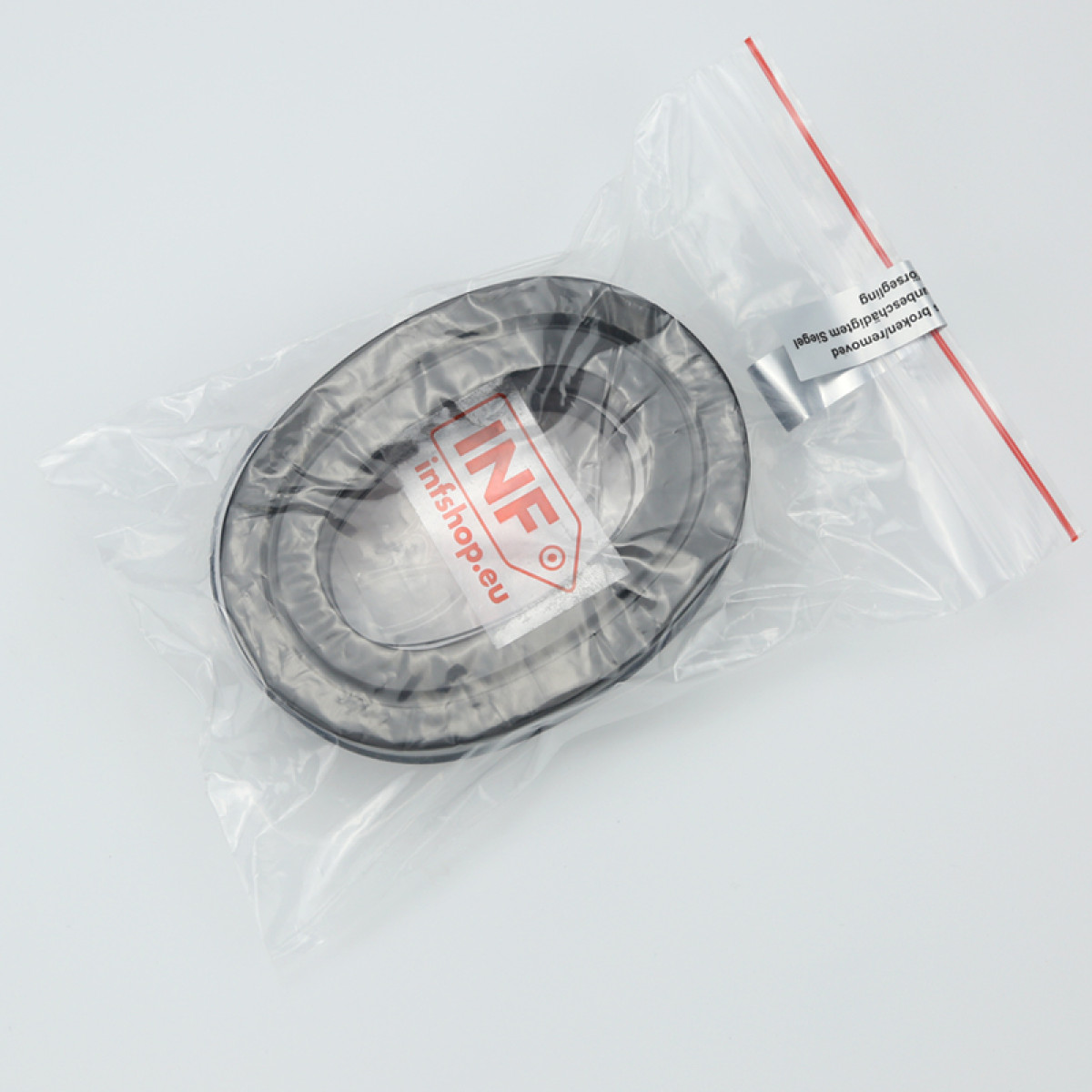 Una guarnizione in gomma nera in un sacchetto di plastica trasparente con etichetta INF. La borsa contiene anche un pezzo di metallo.