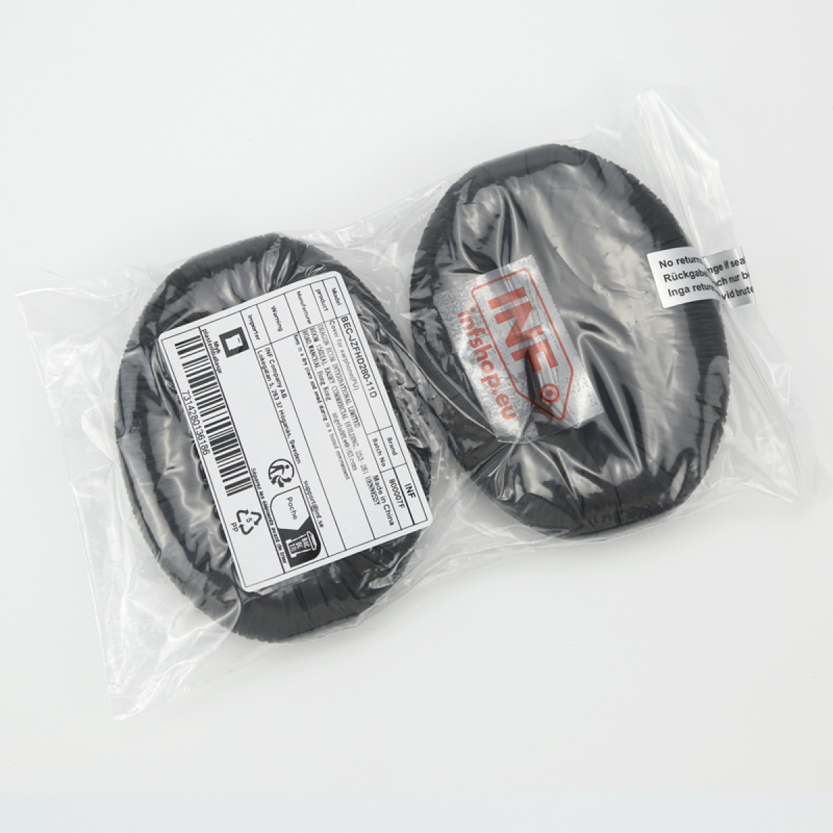 Deux coussinets d'écouteurs noirs dans un emballage plastique avec étiquettes sur une surface blanche.