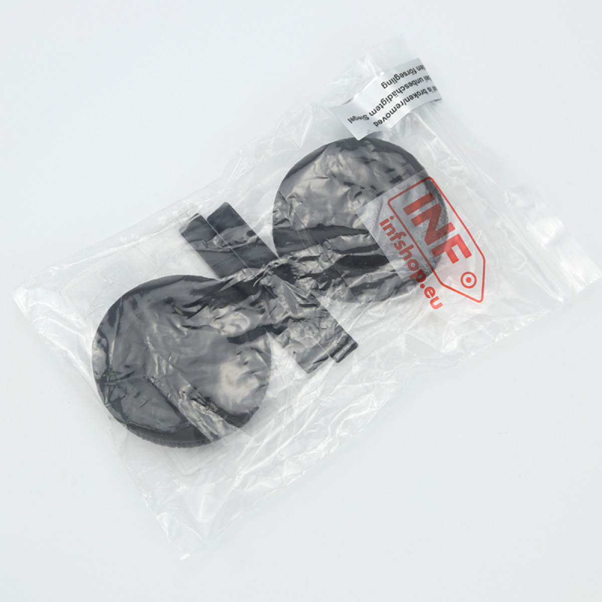 Zwei schwarze, kreisförmige Objekte mit rechteckigen Ansätzen, verpackt in einer durchsichtigen Plastiktüte mit rotem und weißem Logo.