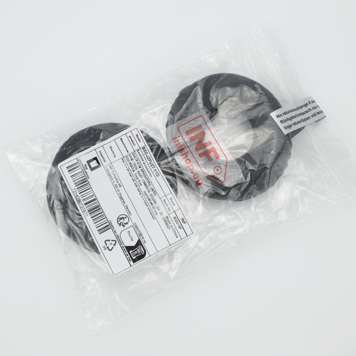 Zwei schwarze Kopfhörerzubehörteile in einer transparenten Plastiktüte mit Produktinformationsetiketten.