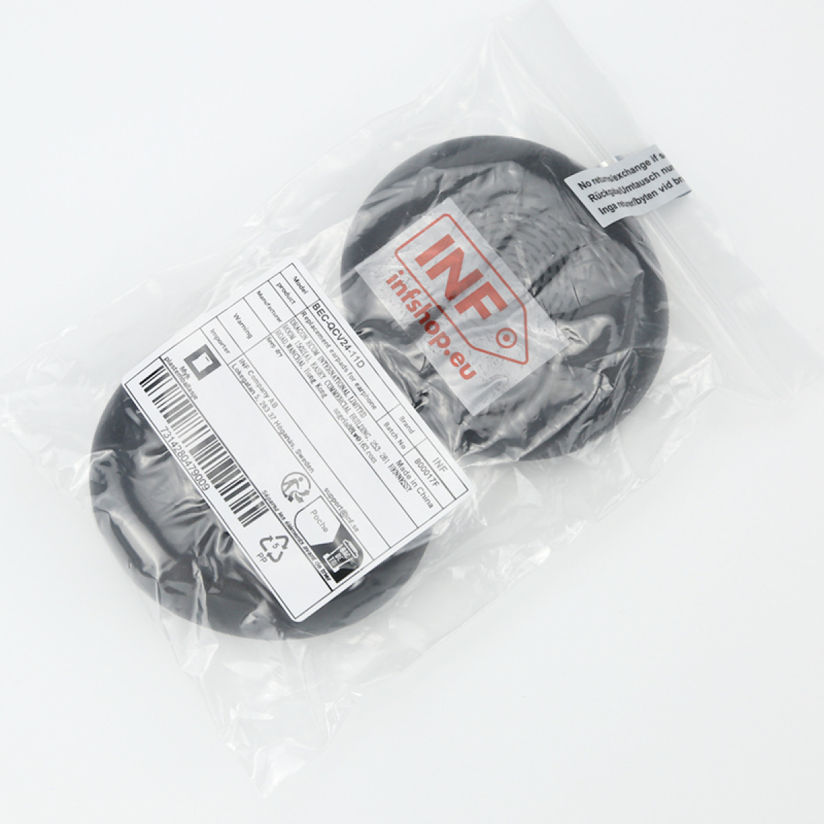 Zwei schwarze, kreisförmige Kopfhörerpolster in einer transparenten Plastiktüte mit Etiketten. Die Etiketten enthalten Produktinformationen.
