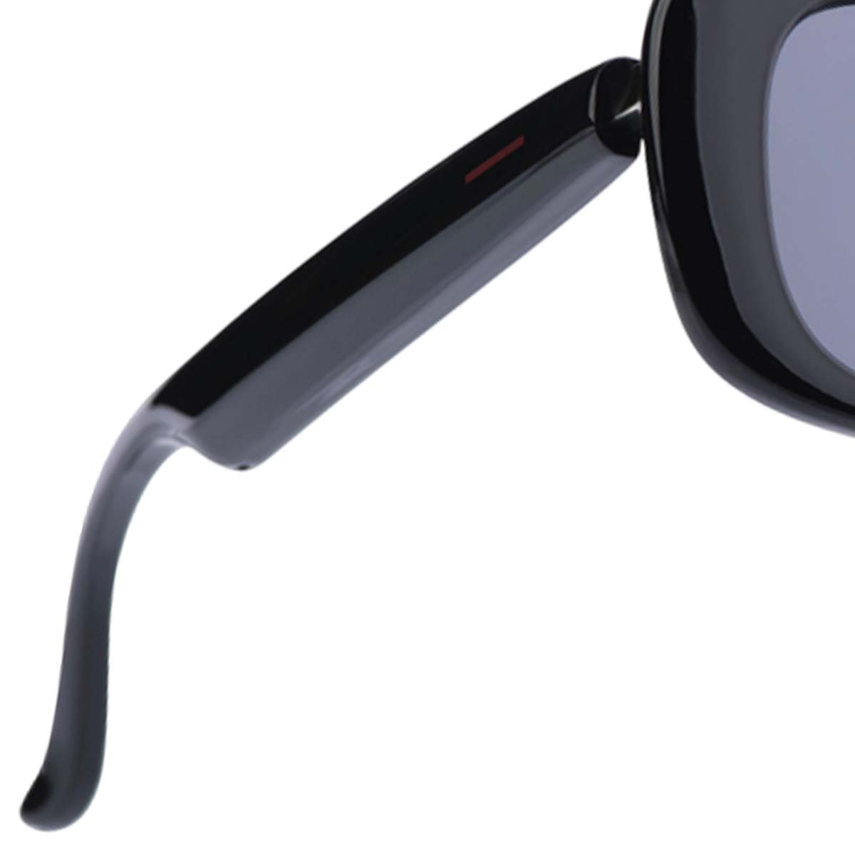 Nahaufnahme einer schwarzen Sonnenbrille. Ein roter Streifen befindet sich am Bügel. Das Glas ist ein gedämpftes Blau-Grau.