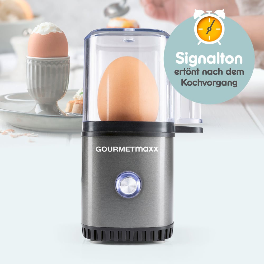 Ein Ei in einem Eierkocher neben einem gekochten Ei in einem grauen Eierbecher. Text: 'Signalton ertönt nach dem Kochvorgang'.