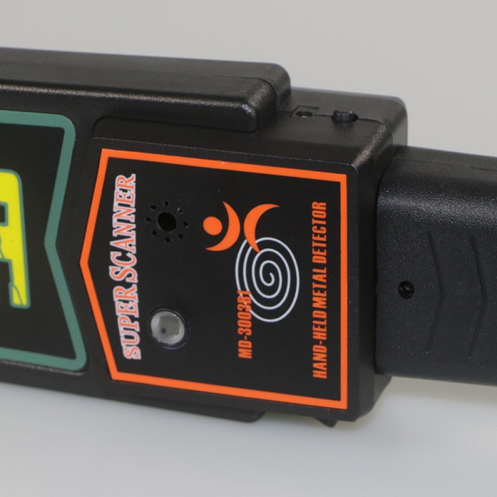 Nahaufnahme eines schwarzen Metalldetektors mit der Aufschrift 'Super Scanner'. Das Gerät hat ein orange-weißes Design mit einem Spulensymbol.