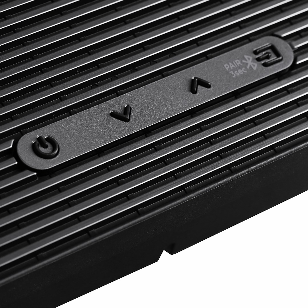 Gros plan d'un appareil noir avec des lignes horizontales. Il possède un bouton d'alimentation, des commandes de volume et un bouton d'appairage Bluetooth.