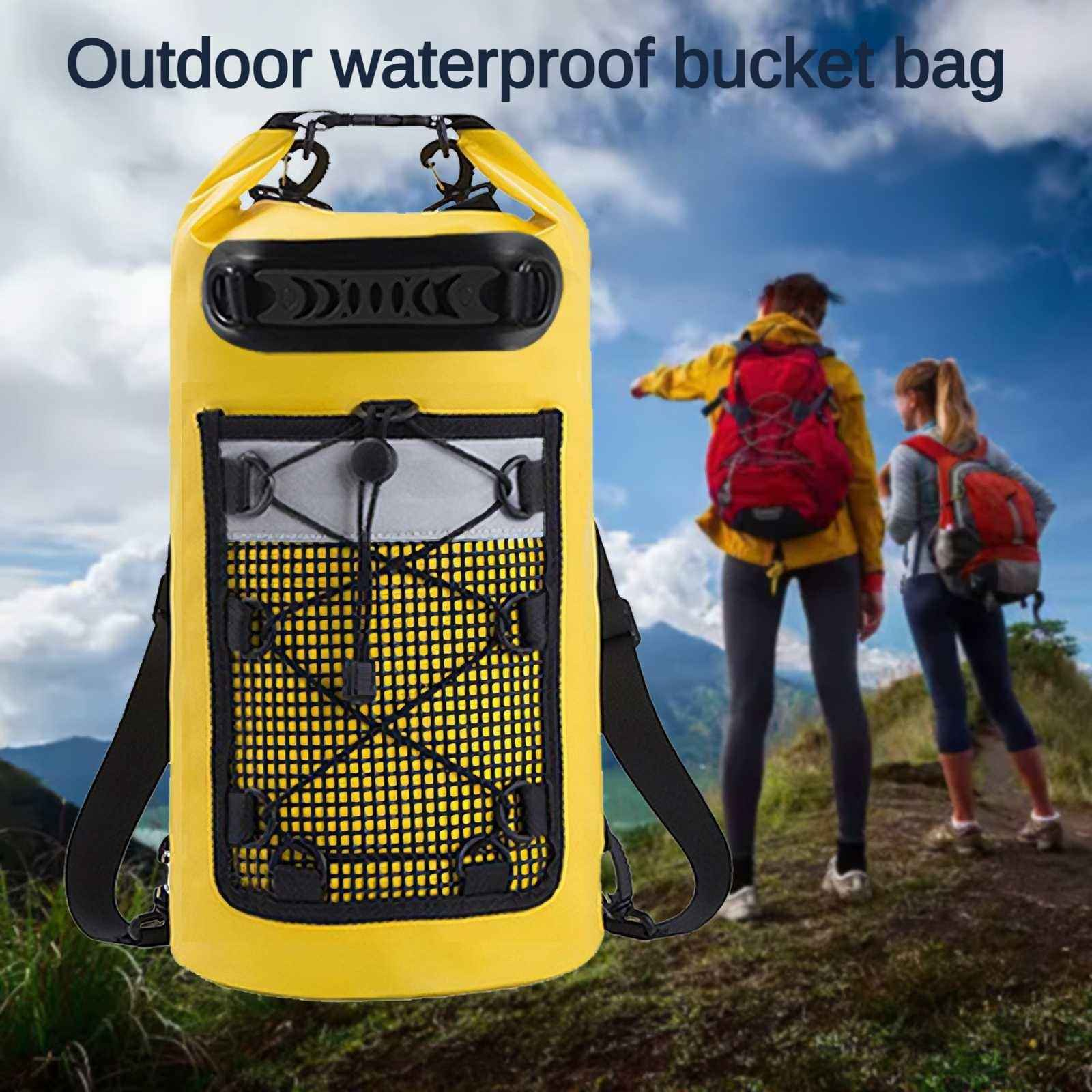 Eine gelbe, wasserdichte Eimertasche mit schwarzen Trägern. Im Hintergrund gehen zwei Wanderer, einer mit rotem Rucksack.