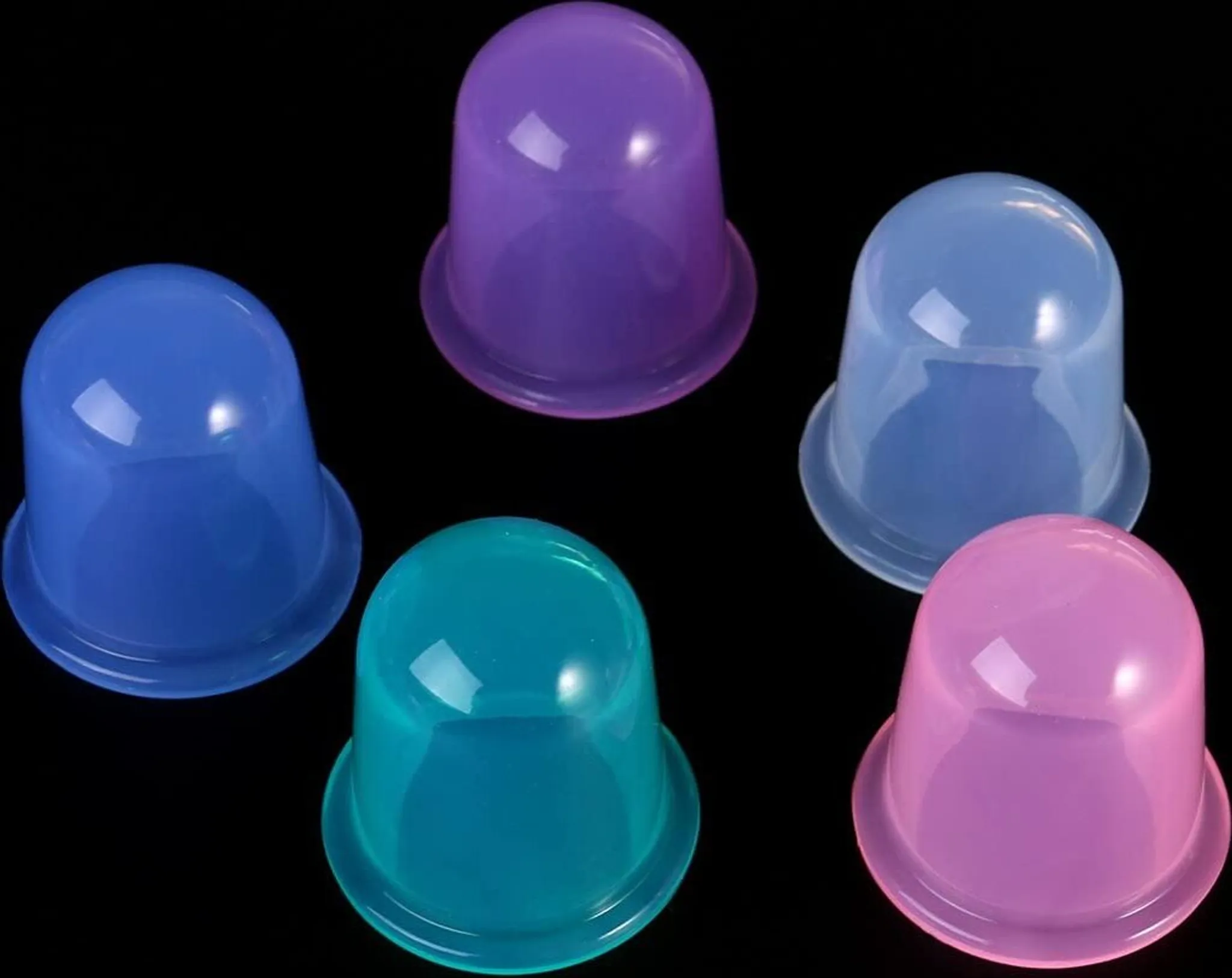 Sechs farbige Schröpftherapiebecher auf schwarzem Hintergrund. Farben: Blau, Lila, Türkis, Rosa und Hellblau.