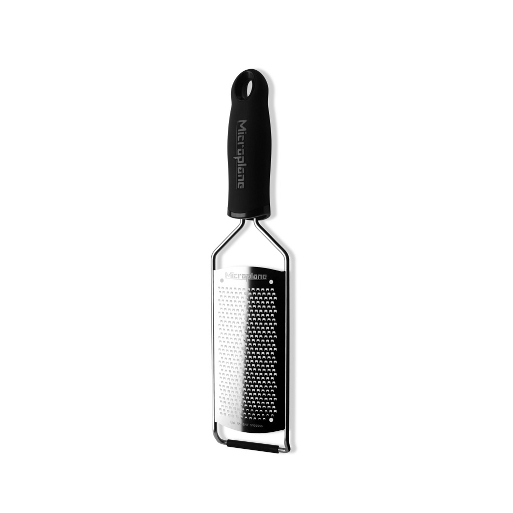 Ein Microplane-Reibeisen, schwarzer Griff, silberner Rahmen und eine rechteckige Reibefläche. Die Reibe steht auf weißem Grund.