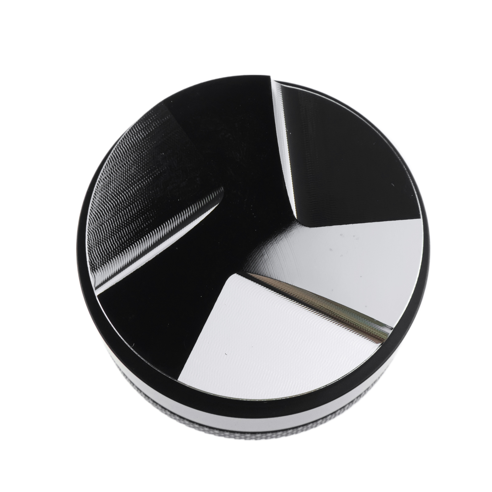 Ein metallischer Grinder mit kreisförmigem Design. Er hat schwarze und silberne Abschnitte, einen strukturierten Rand und einen weißen Hintergrund.