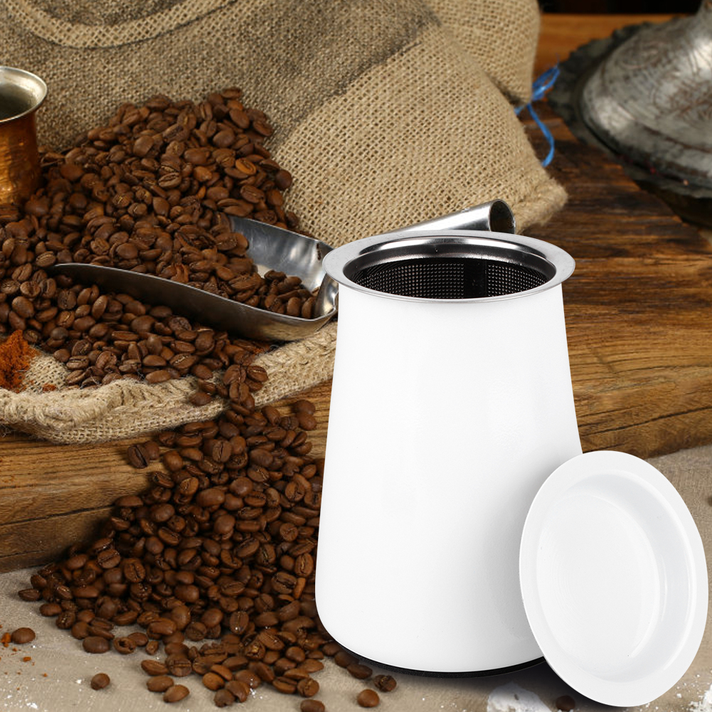 Ein weißer Kaffeefilter mit Deckel. Kaffeebohnen sind verstreut. Eine Schaufel, ein Jutesack und ein Holzbrett im Hintergrund.