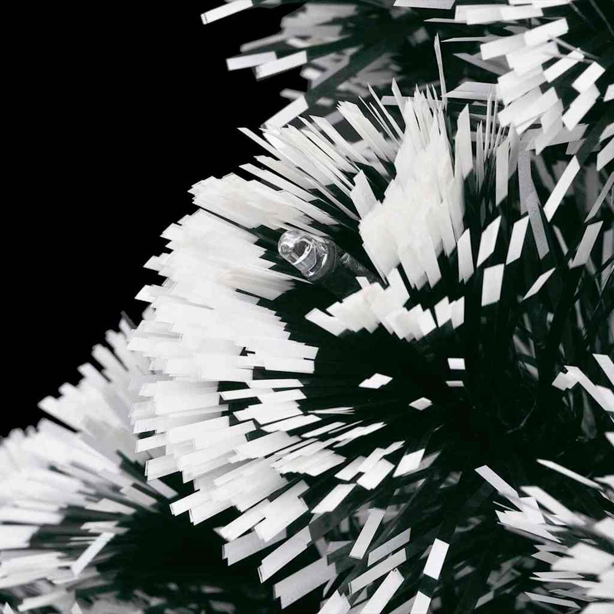 Primo piano di un ramo di albero di Natale. Tinsel bianco e nero con una singola lampadina su sfondo nero.