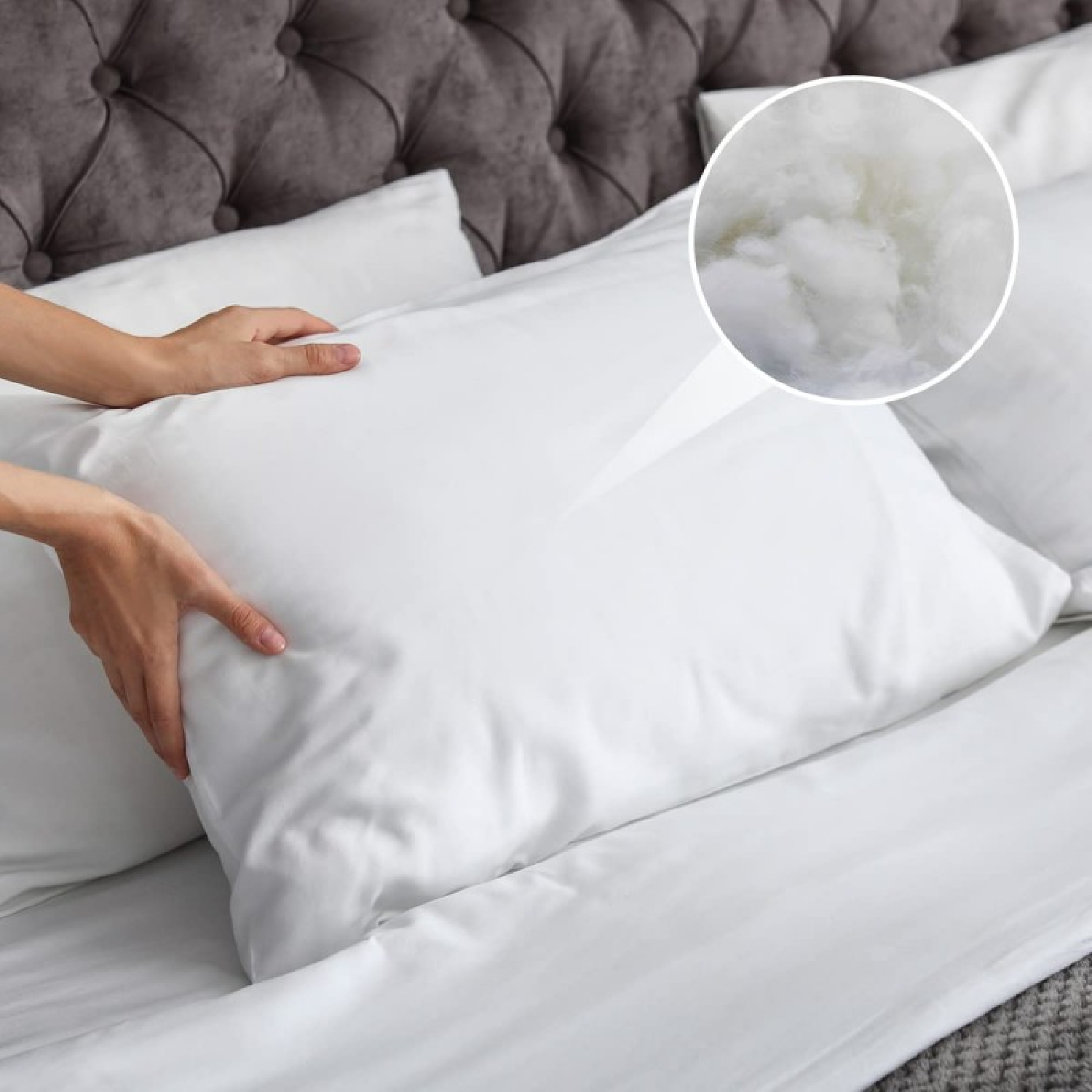 Manos ajustando una almohada blanca en una cama. Un primer plano muestra el relleno esponjoso. Un cabecero acolchado está en el fondo.