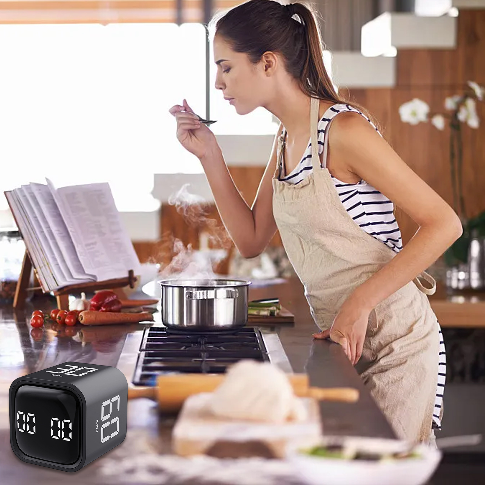 Eine Frau in der Küche probiert Essen aus einem Topf. Im Vordergrund ein Timer, im Hintergrund ein Kochbuch.