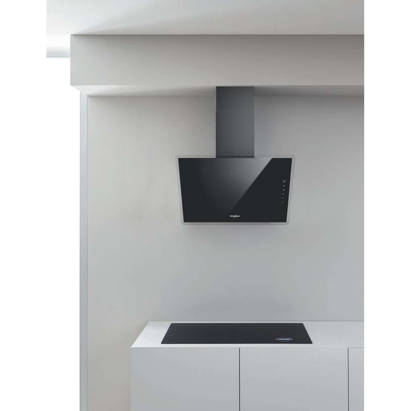 Een moderne keuken met een zwarte afzuigkap boven een zwart kookveld. Witte kasten en muren creëren een minimalistisch design.