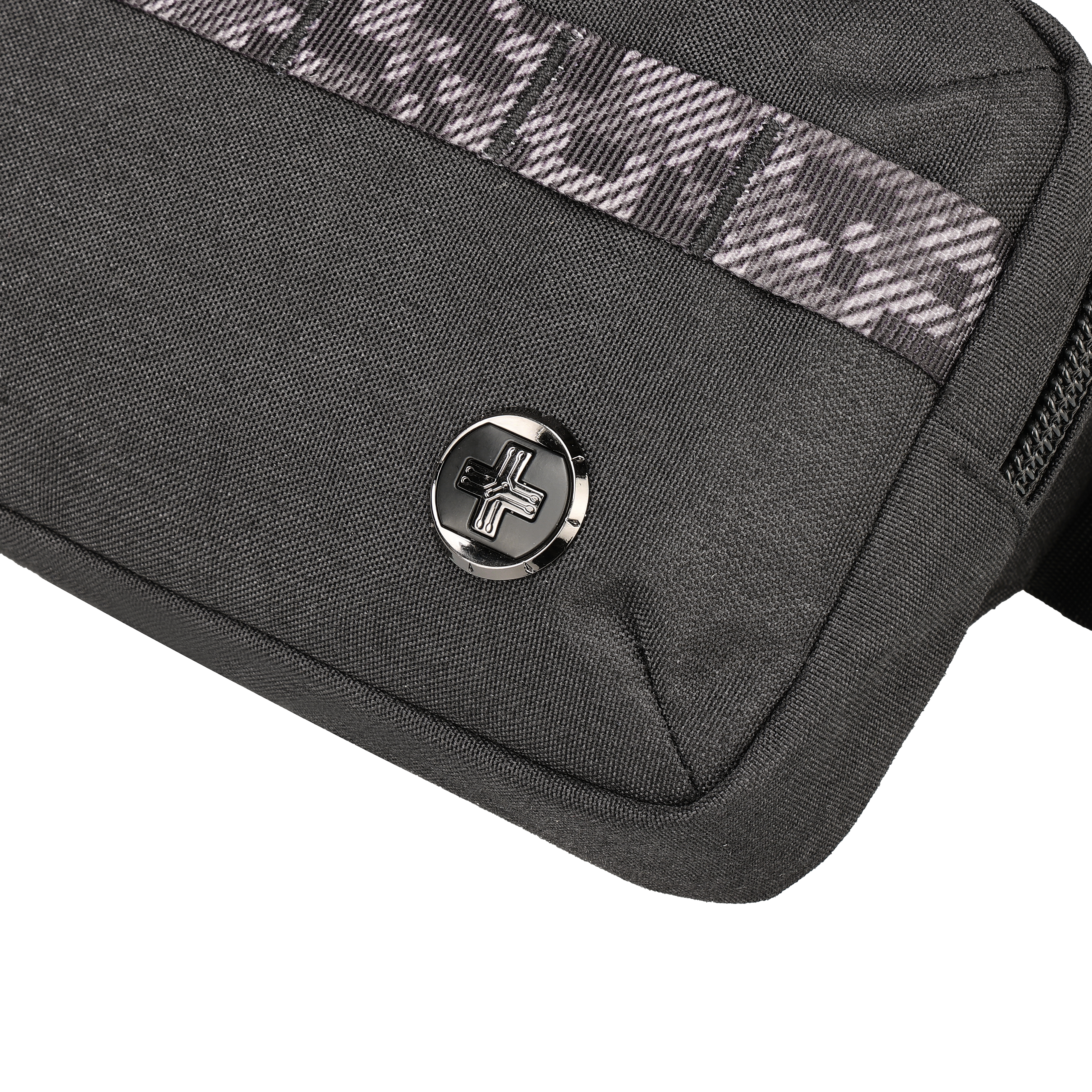 Primo piano di una borsa nera con emblema argentato e cinturino fantasia. Sono visibili una cerniera e un angolo.