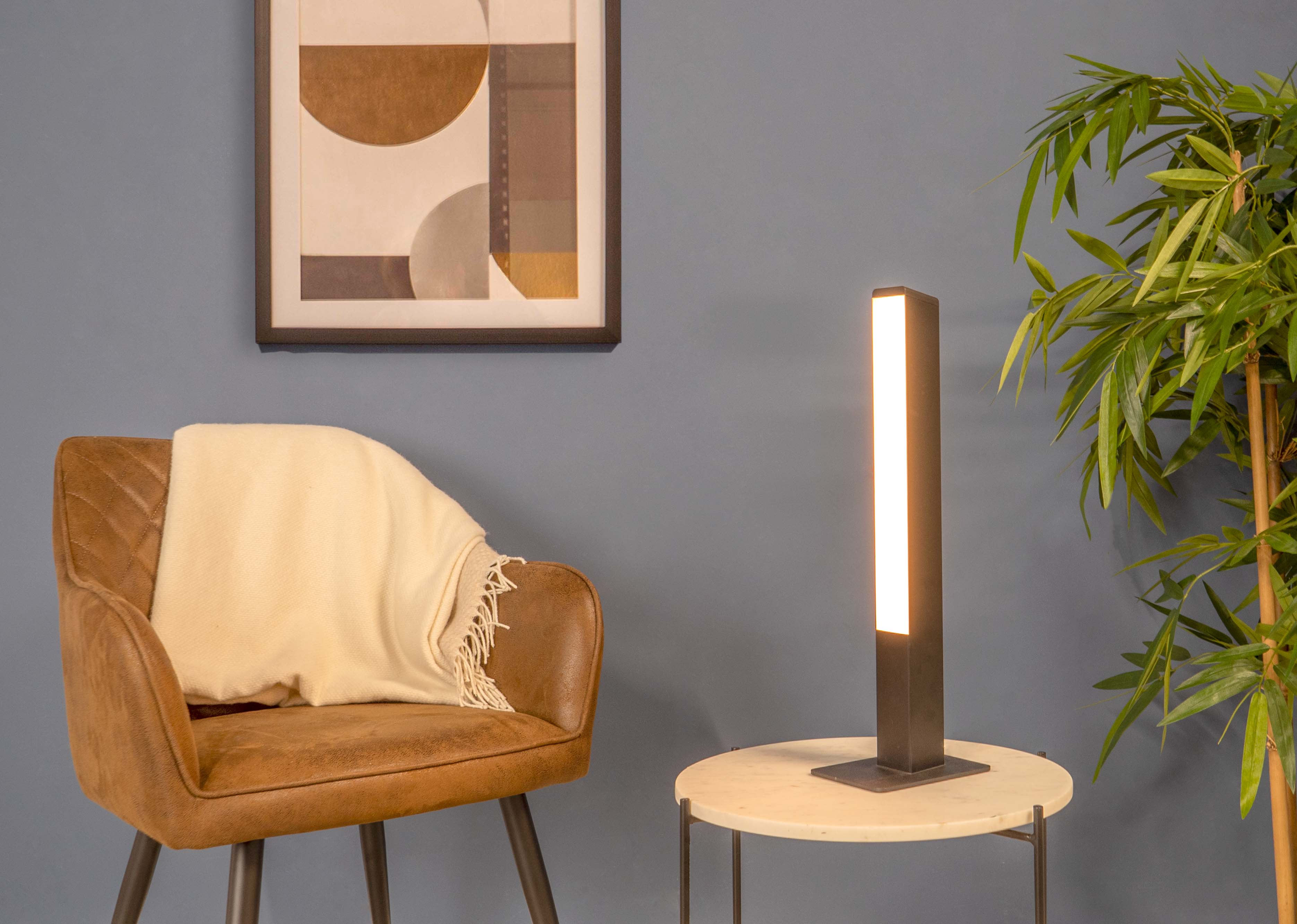 Eine moderne Innenszene mit Stuhl, Lampe, Kunst und Pflanzen. Die Beleuchtung ist weich und warm.