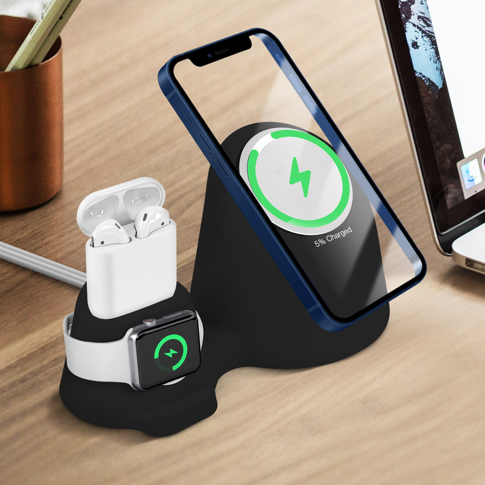 Una estación de carga para teléfono, reloj y auriculares. El teléfono y el reloj muestran la carga. Auriculares en un estuche. Todo sobre un escritorio de madera.