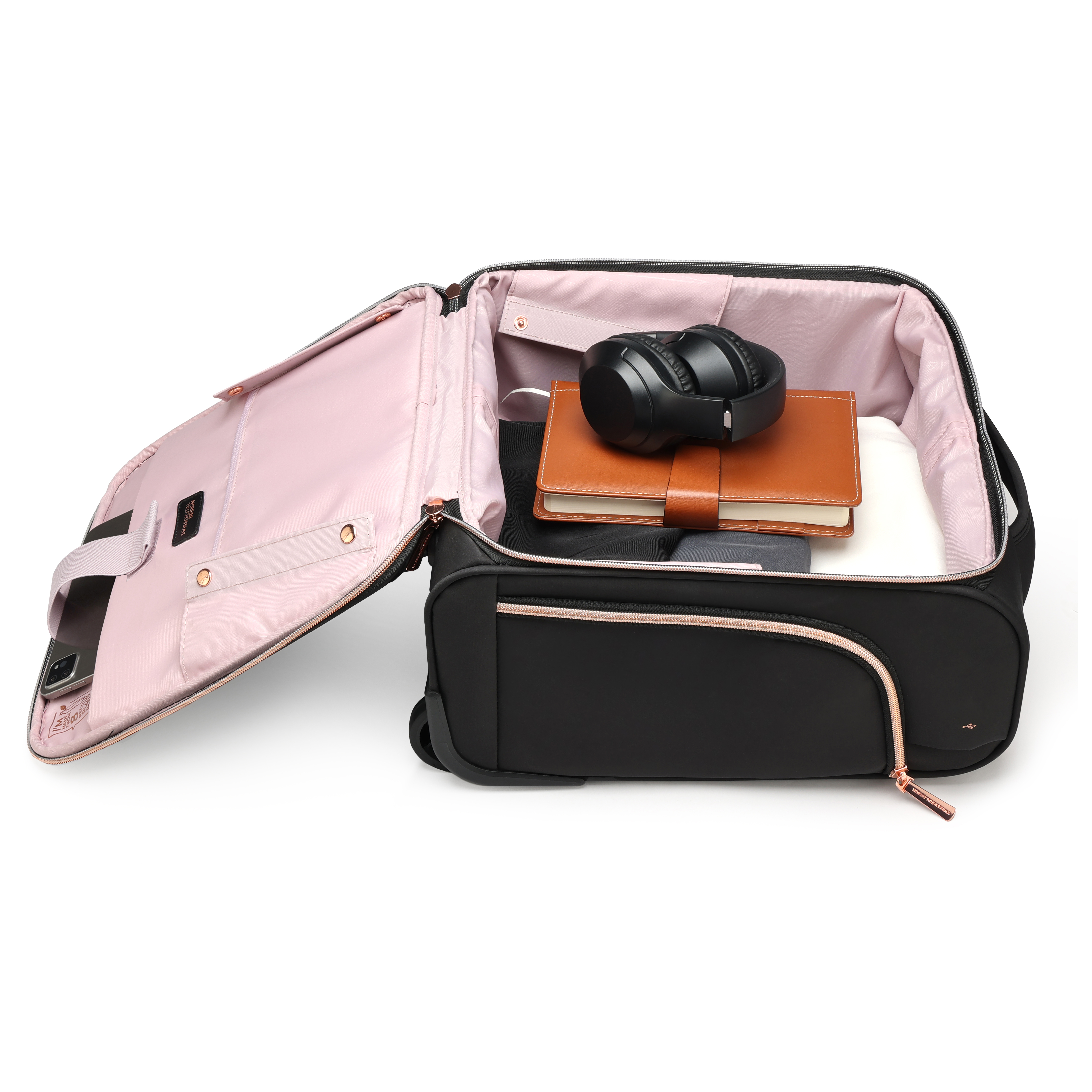 Valigia nera aperta con interno rosa. Contiene cuffie, un taccuino marrone e un capo bianco. È visibile anche un telefono.