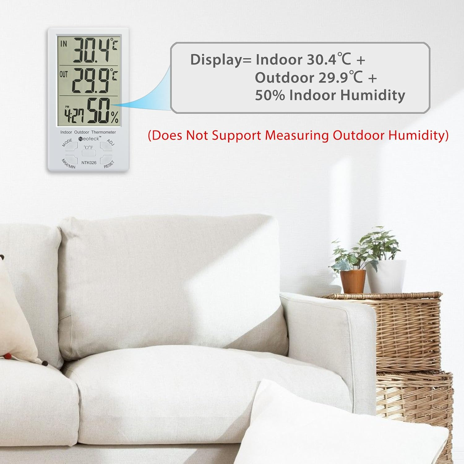 Ein Digitalthermometer zeigt Innen-/Außentemperaturen und Luftfeuchtigkeit an. Im Hintergrund befinden sich ein weißes Sofa und Weidenkörbe.
