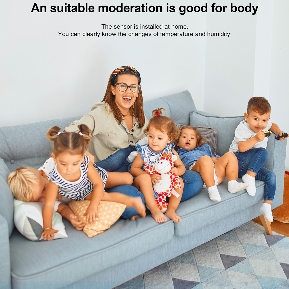 Eine Frau und fünf Kinder sitzen auf einem grauen Sofa. Die Kinder spielen, eines hält ein Spielzeugauto und ein anderes ein Stofftier.