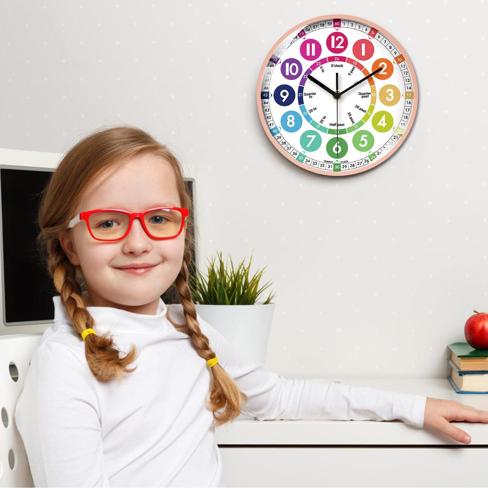 Ein Mädchen mit Zöpfen und roter Brille lächelt. Eine bunte Uhr hängt darüber und zeigt die Zeit an.