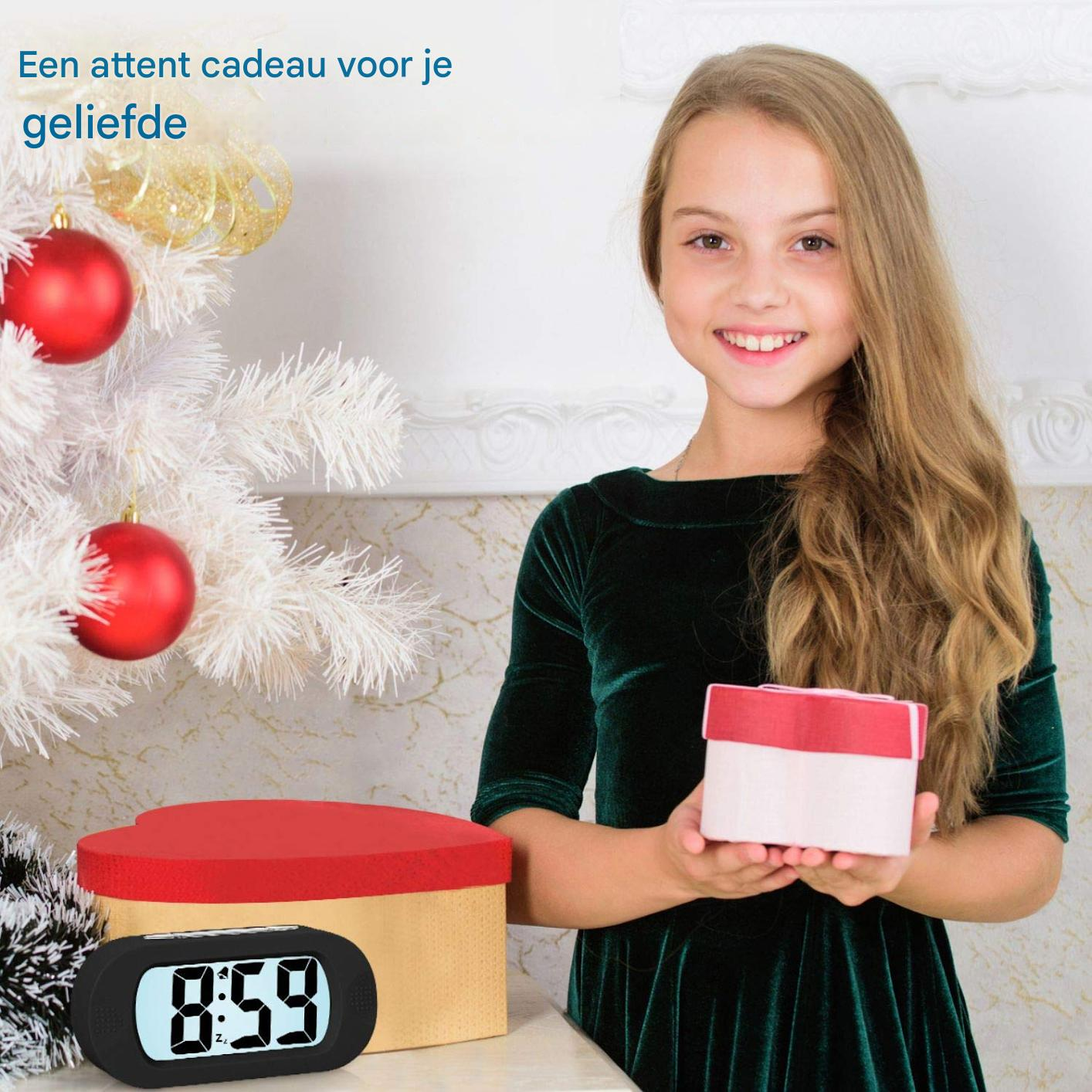Una ragazza in abito verde tiene una scatola regalo. Un orologio segna le 8:59. Un albero di Natale con ornamenti rossi e una scatola regalo sullo sfondo.