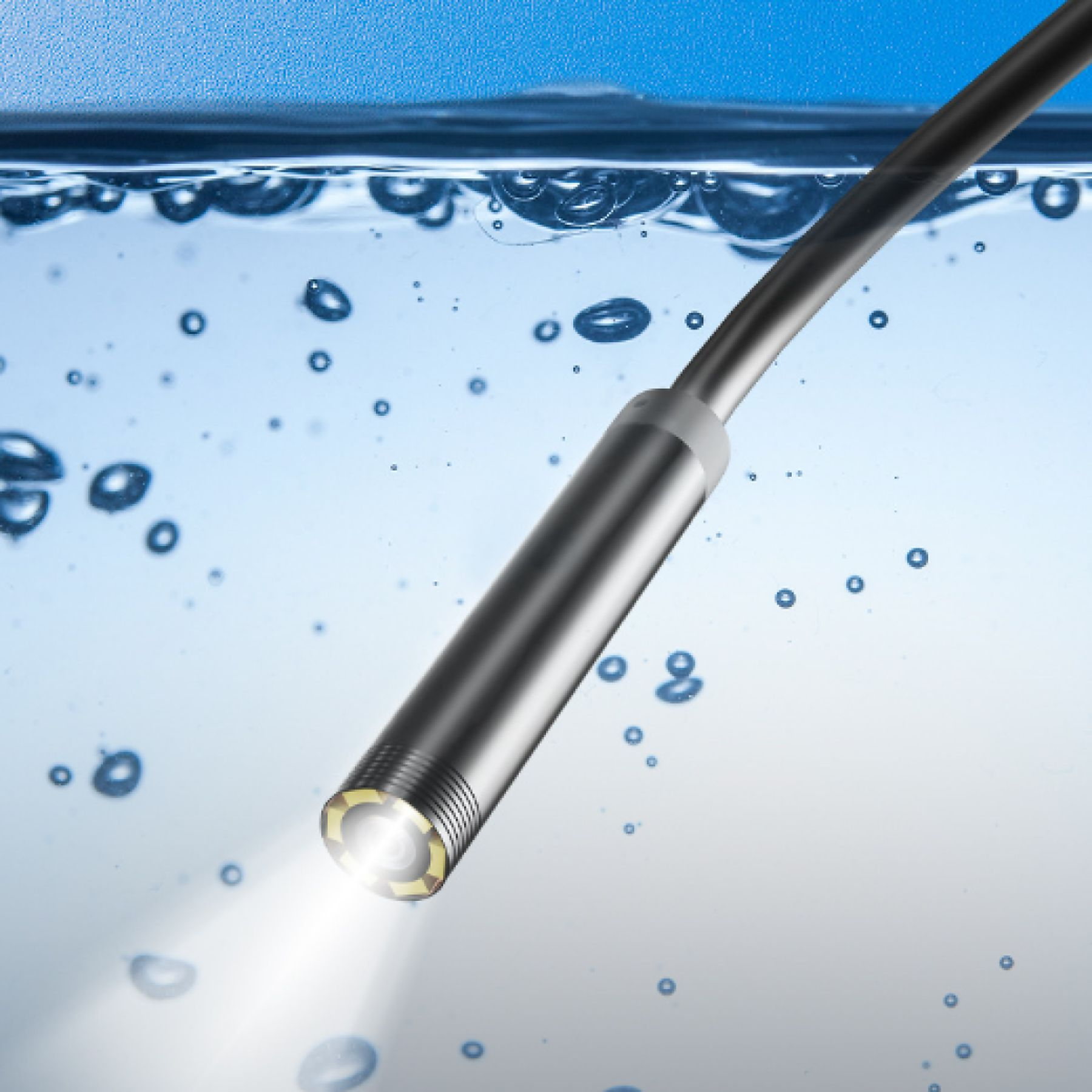 Ein Metallendoskop, das in Wasser getaucht ist und helles Licht aussendet. Blasen schweben im blauen Wasser.
