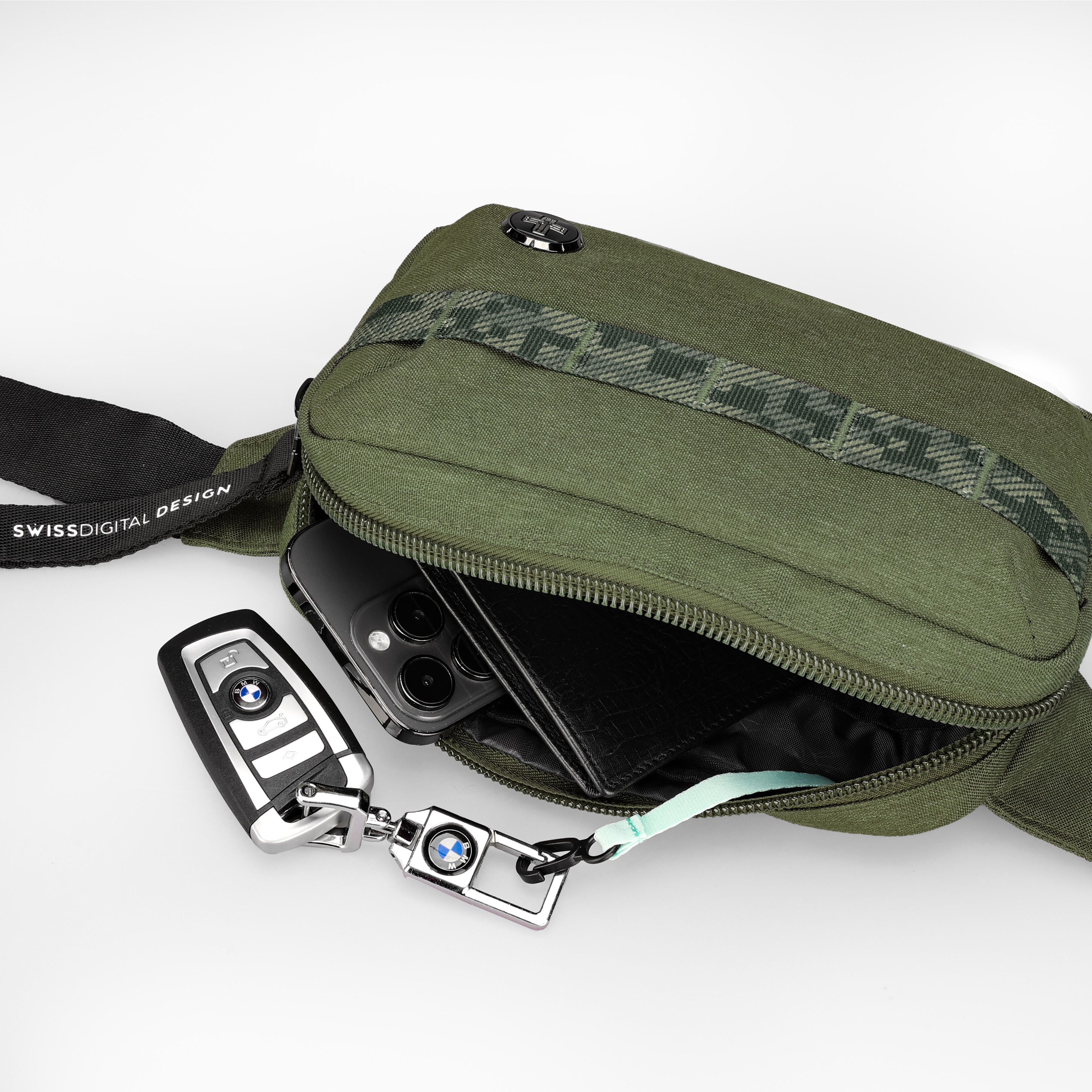 Borsa verde con telefono, portafoglio e chiavi dell'auto. Cinturino nero con testo bianco. Sfondo bianco.