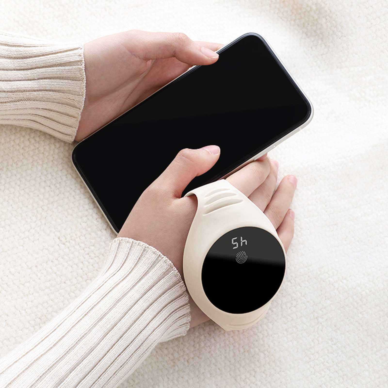 Hände halten ein Smartphone und einen weißen Handwärmer. Der Hintergrund ist eine weiße, strukturierte Oberfläche.