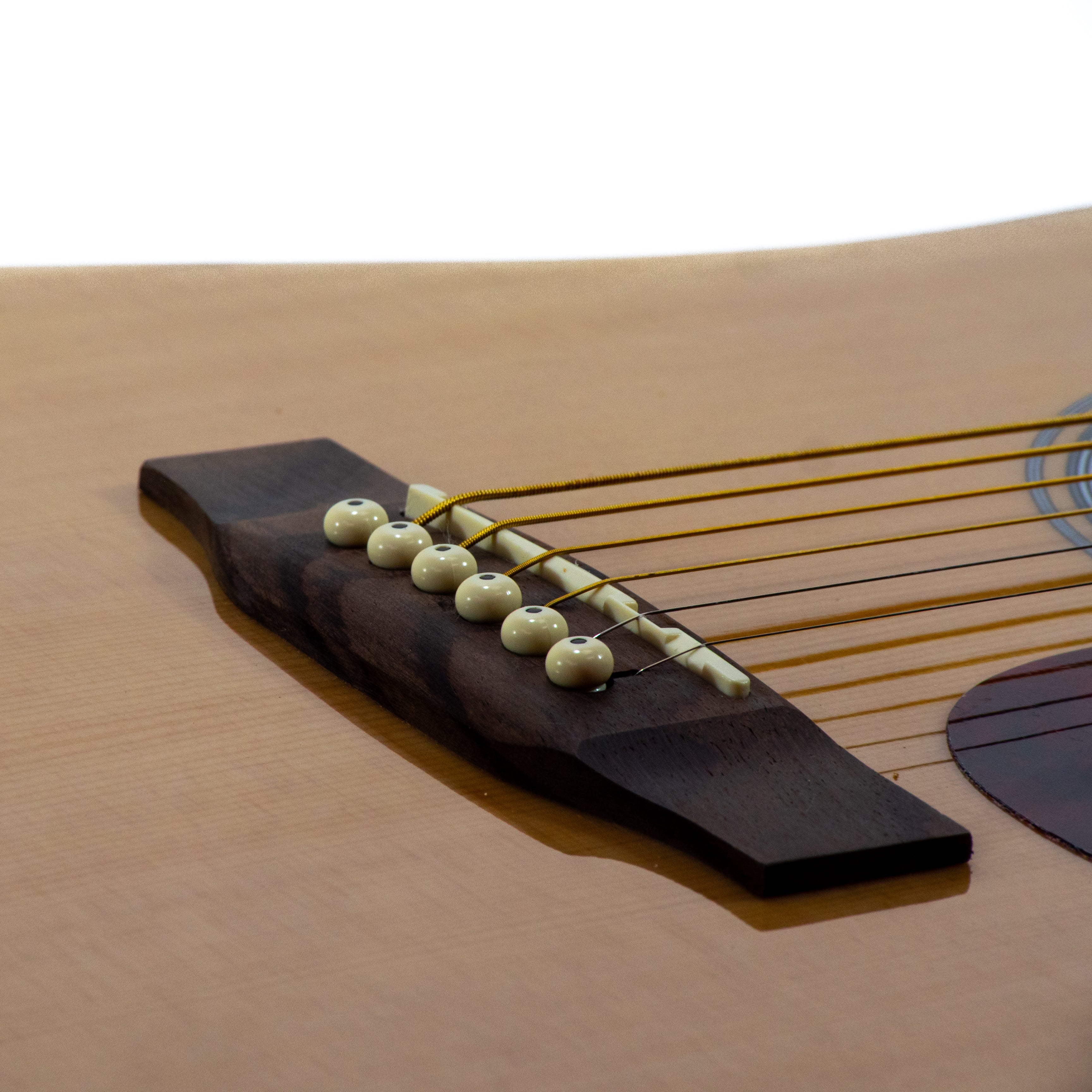Nahaufnahme einer Gitarre. Fokus auf die Brücke mit Saiten, der Korpus ist hellbraun.