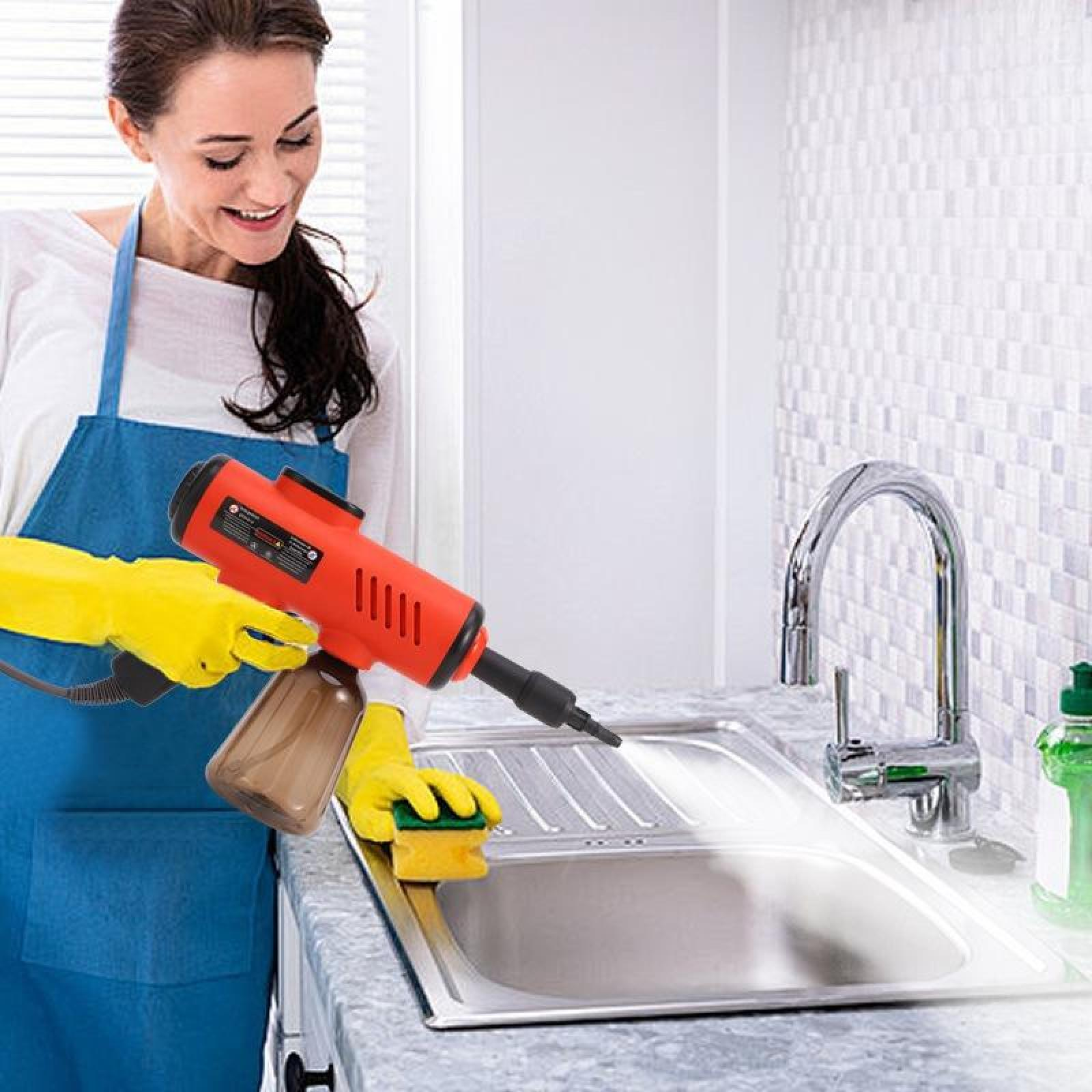Eine Frau in Schürze und gelben Handschuhen benutzt ein rotes Reinigungsgerät an einem Waschbecken. Schwamm und Flasche sind sichtbar.