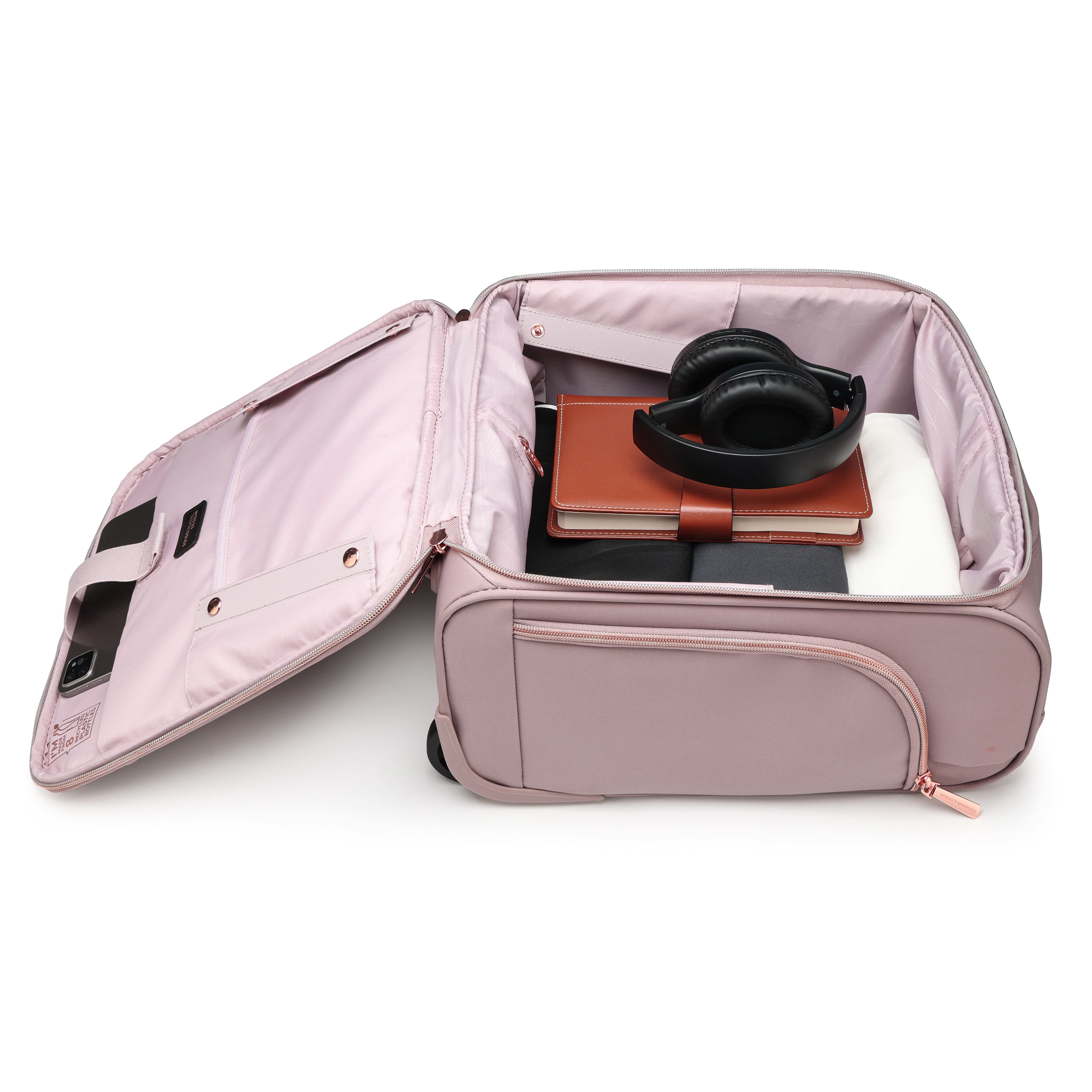 Valigia aperta con oggetti dentro: cuffie, quaderno, vestiti. Valigia rosa su sfondo bianco.