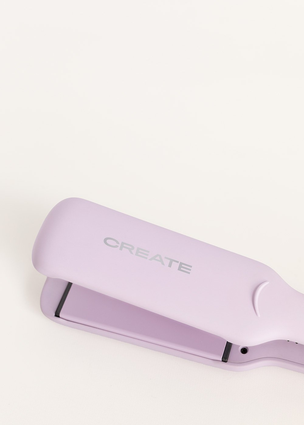 Primer plano de una plancha de pelo lila, con la palabra 'CREATE' impresa, sobre un fondo blanco.