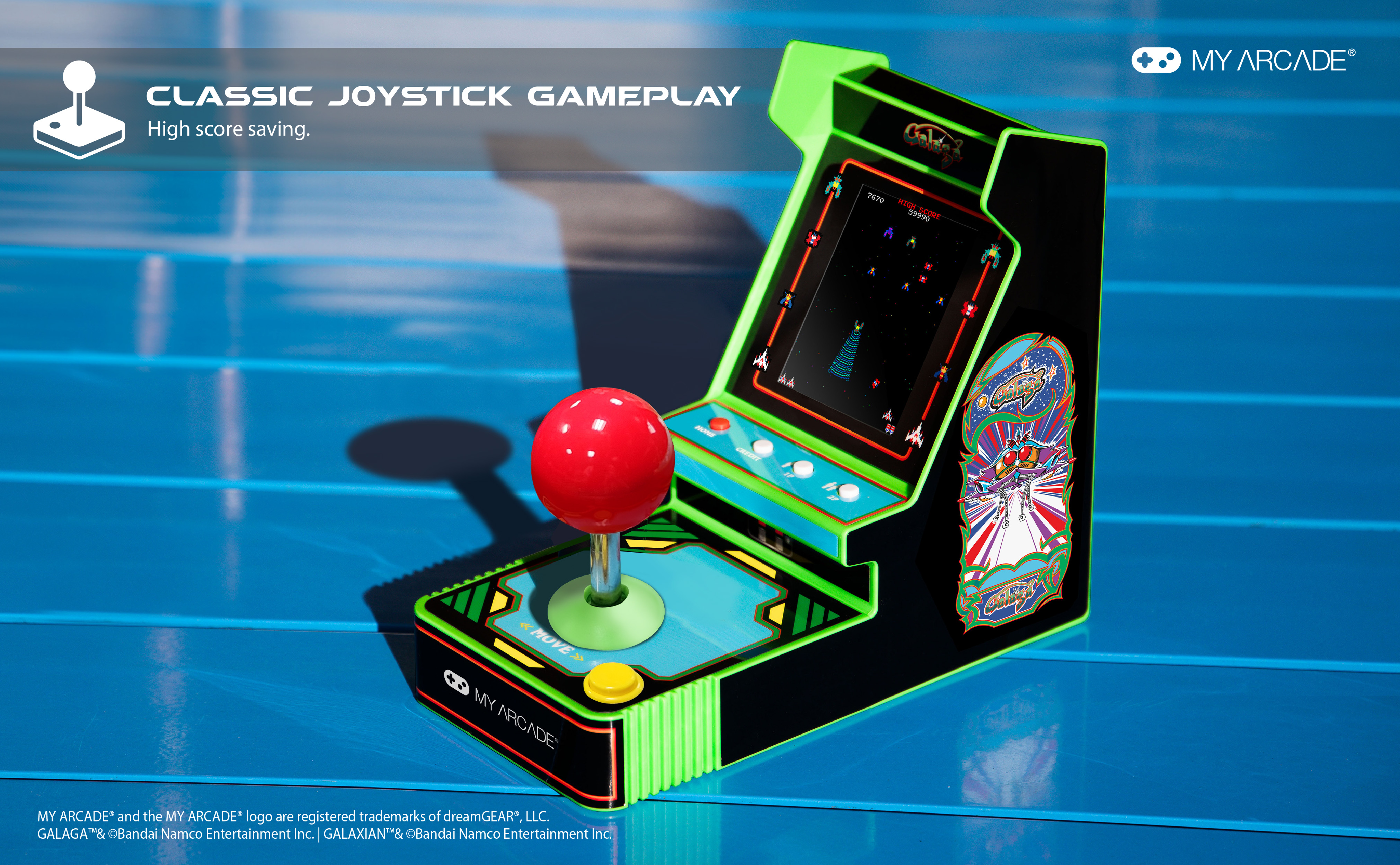 Mini cabinato arcade con joystick rosso, bordi verdi e schermo di gioco. Sfondo blu.