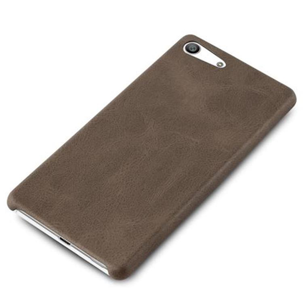 Se muestra una funda de teléfono de cuero marrón, ligeramente en ángulo. Tiene una cámara y un flash. La funda tiene una superficie texturizada.