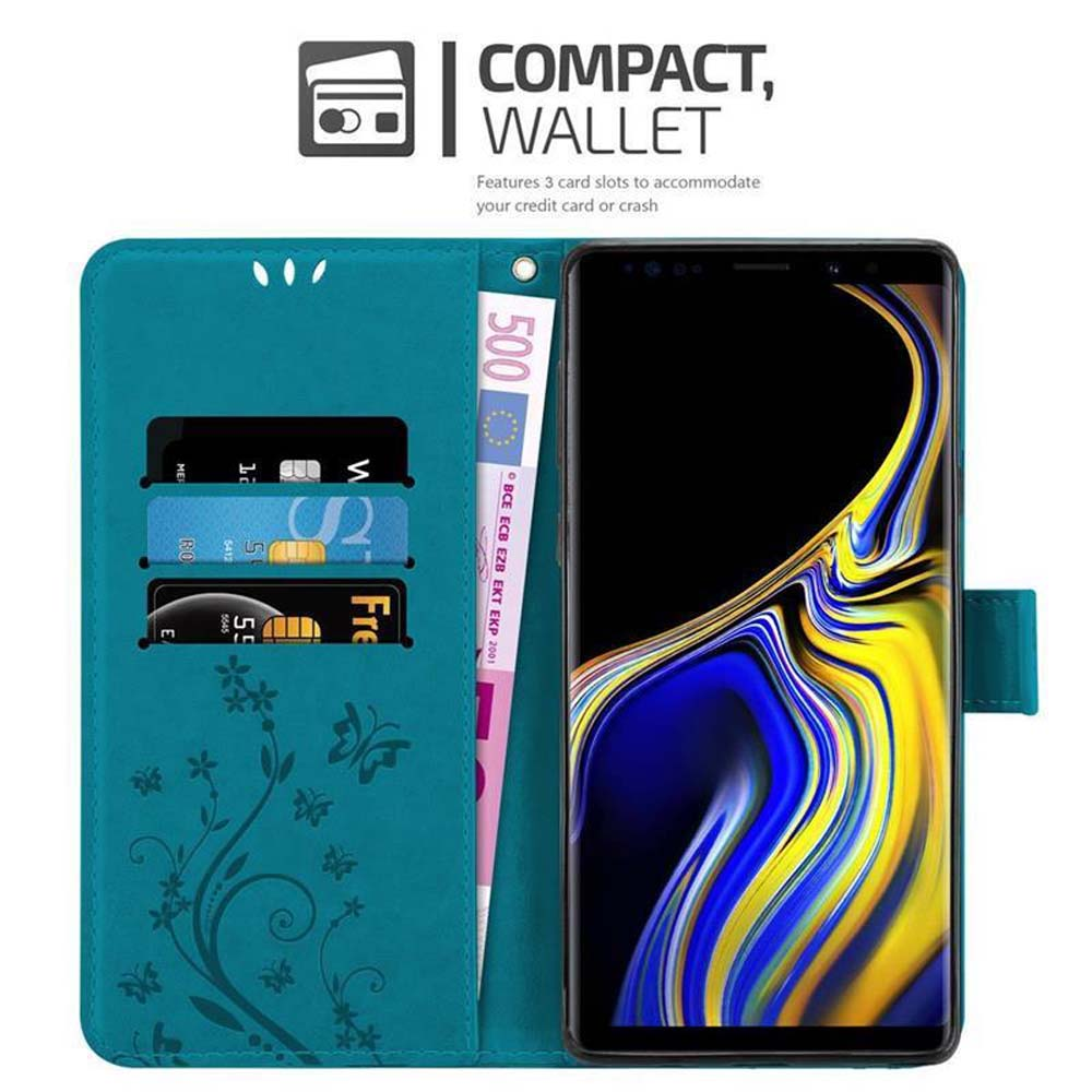 Eine türkisblaue Geldbörse mit Kartenfächern, einem 500-Euro-Schein und einem Smartphone. Die Geldbörse hat Blumendesigns und hält Karten.
