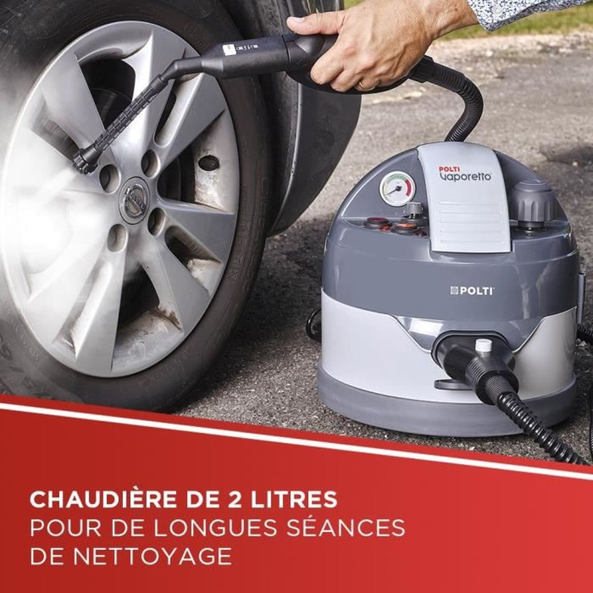 Osoba używa parownicy do czyszczenia opony samochodowej. Czyszczący jest szary i biały, z czarnym wężem. Para jest widoczna.