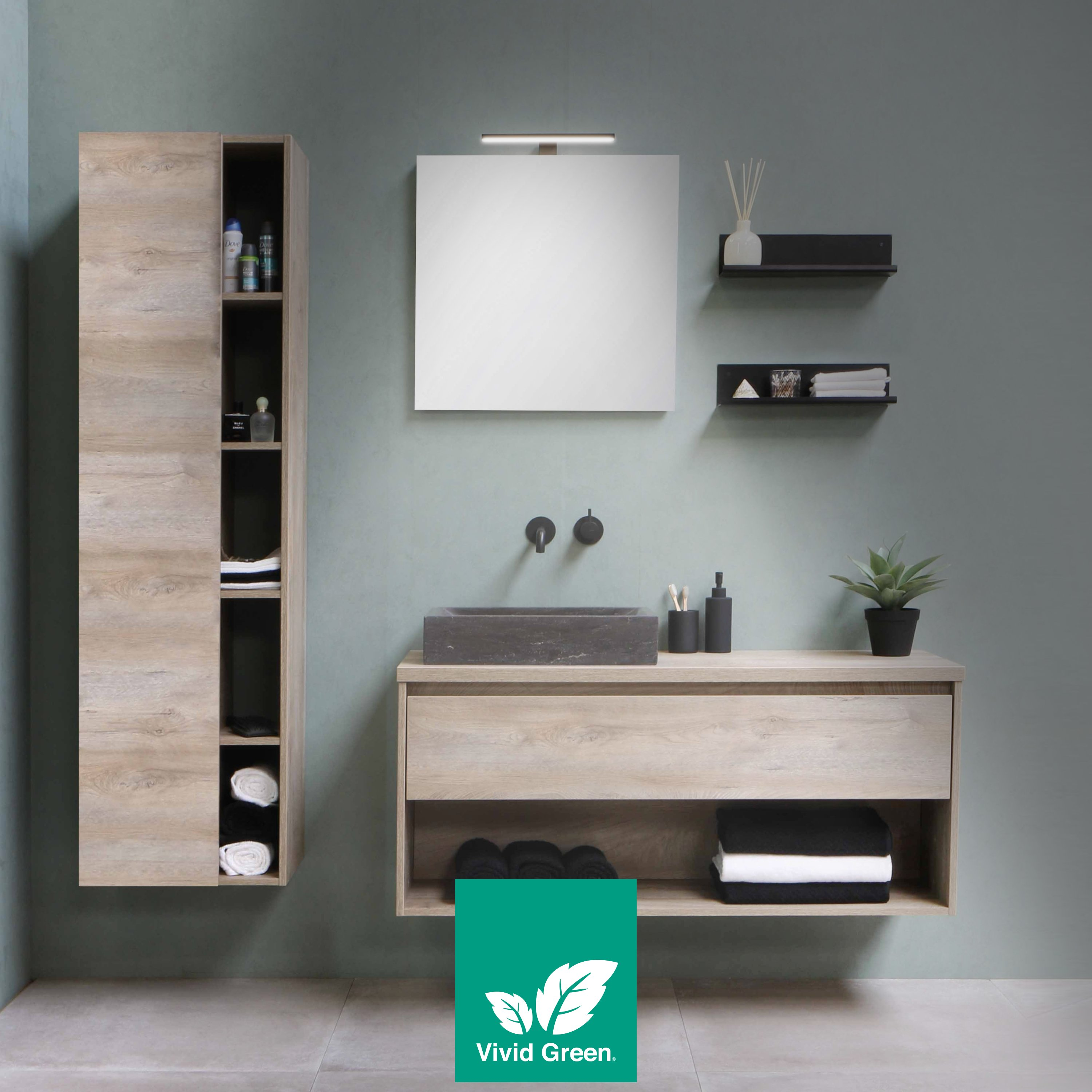 Een moderne badkamer met licht houten kasten, een spiegel, wastafel en planken. Een plant en handdoeken zijn zichtbaar.