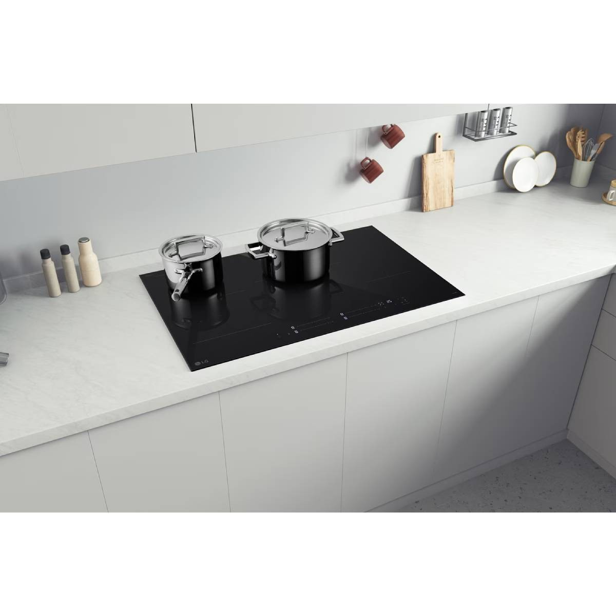 Una cucina moderna con un piano cottura nero. Due pentole sono sul piano cottura. Armadi e piano di lavoro bianchi. Utensili da cucina visibili.